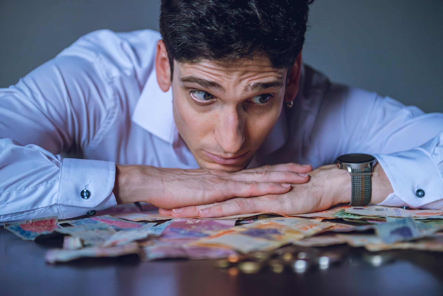 Pessoa analisando cotações de moedas em uma mesa com computador e documentos