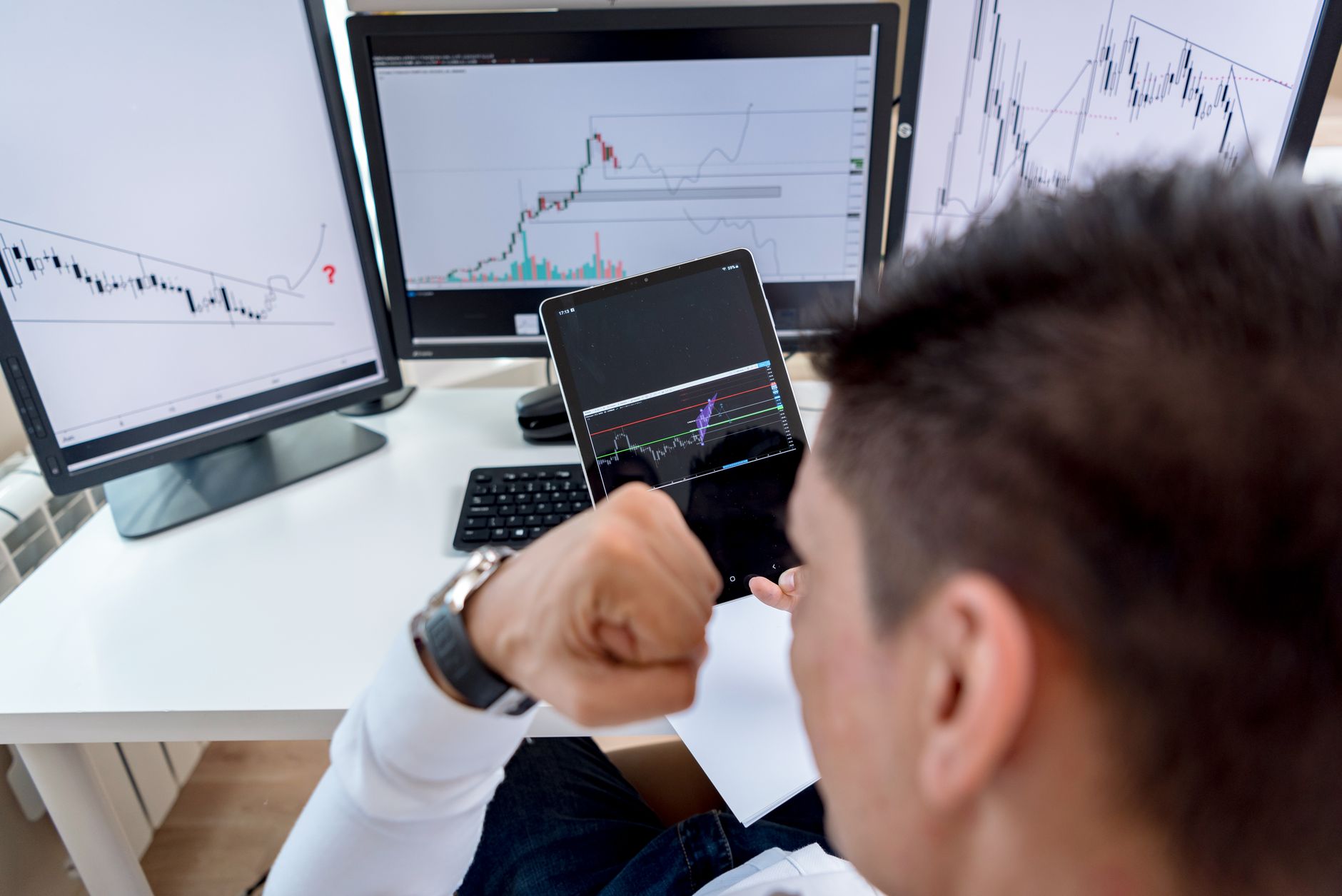 Pessoa analisando gráficos do euro e do dólar em uma mesa de trabalho