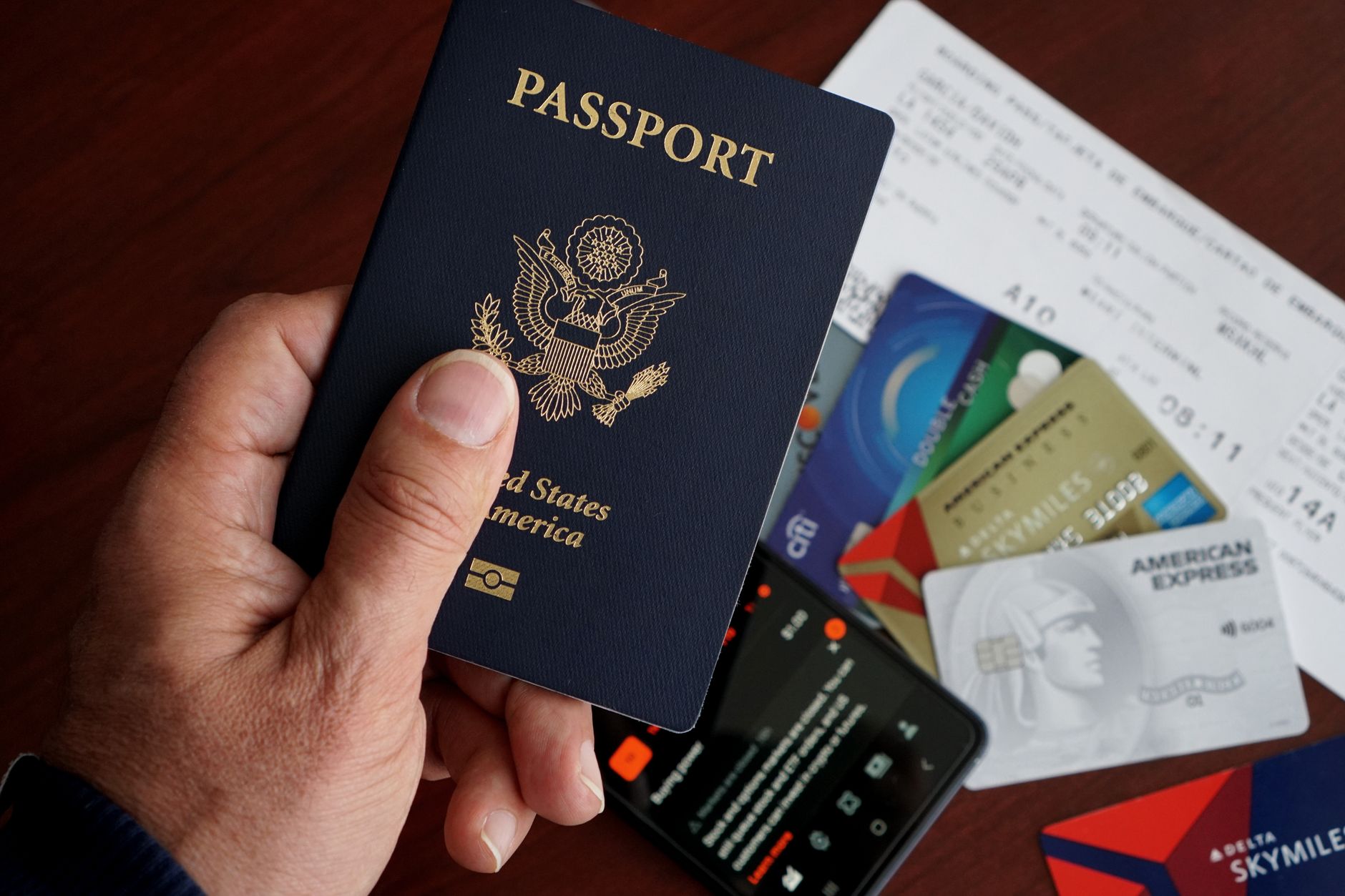 Pessoa consultando a cotação do euro em um celular diante de documentos de viagem