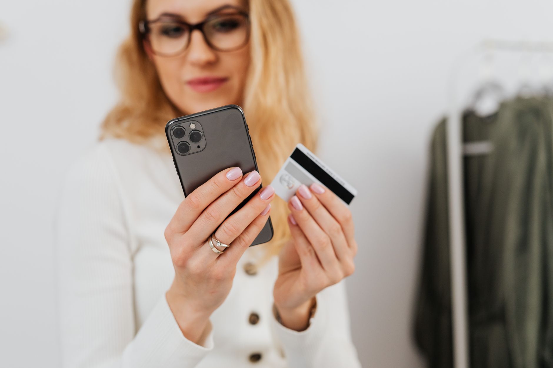 Como freelancer pode receber pagamentos em euro do exterior A woman holding a smartphone and credit card, engaging in online shopping indoors.
