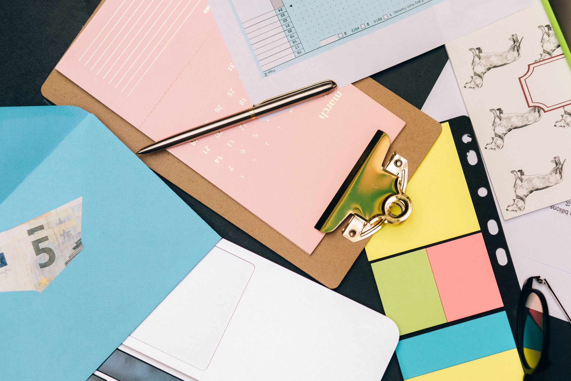 Como funcionam os fundos de investimento em euro Neatly arranged desk supplies with clipboard, euro bill, and colorful notes.