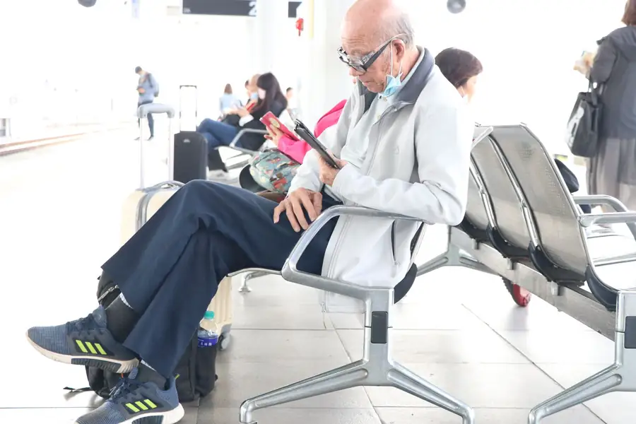 Passageira usando o celular em um terminal de aeroporto com bagagem ao lado