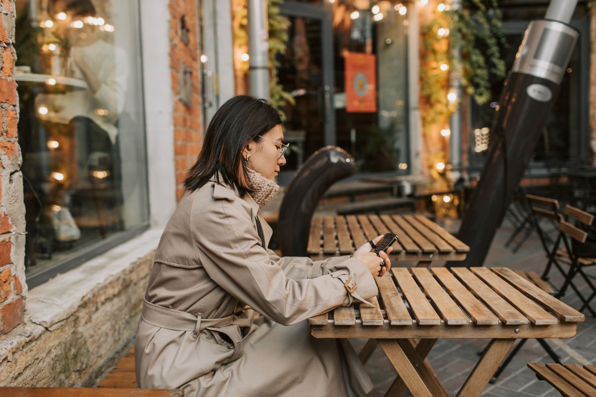 Pessoa segurando notas de euro e passaporte em uma mesa de café europeu