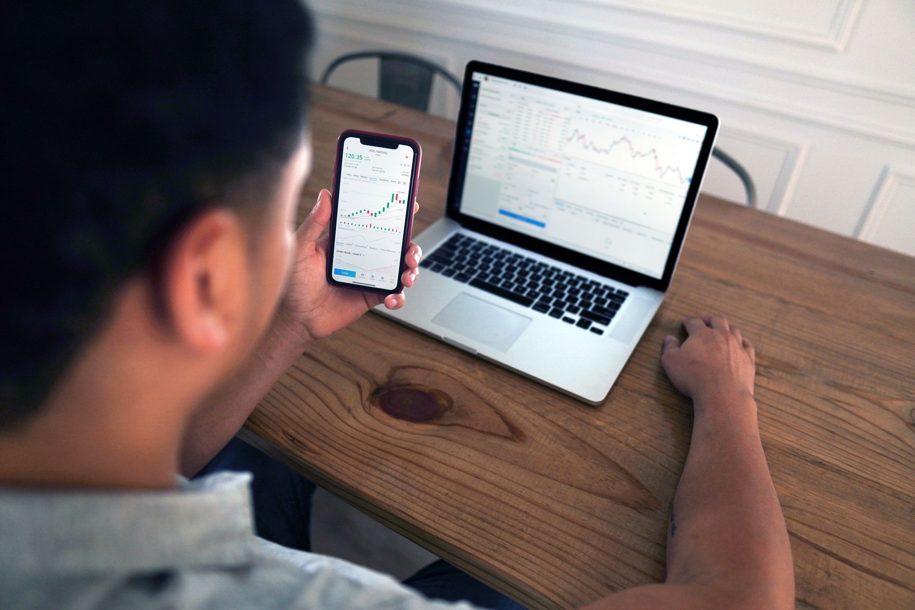 Pessoa analisando gráficos de investimentos internacionais em um computador portátil sobre a mesa.