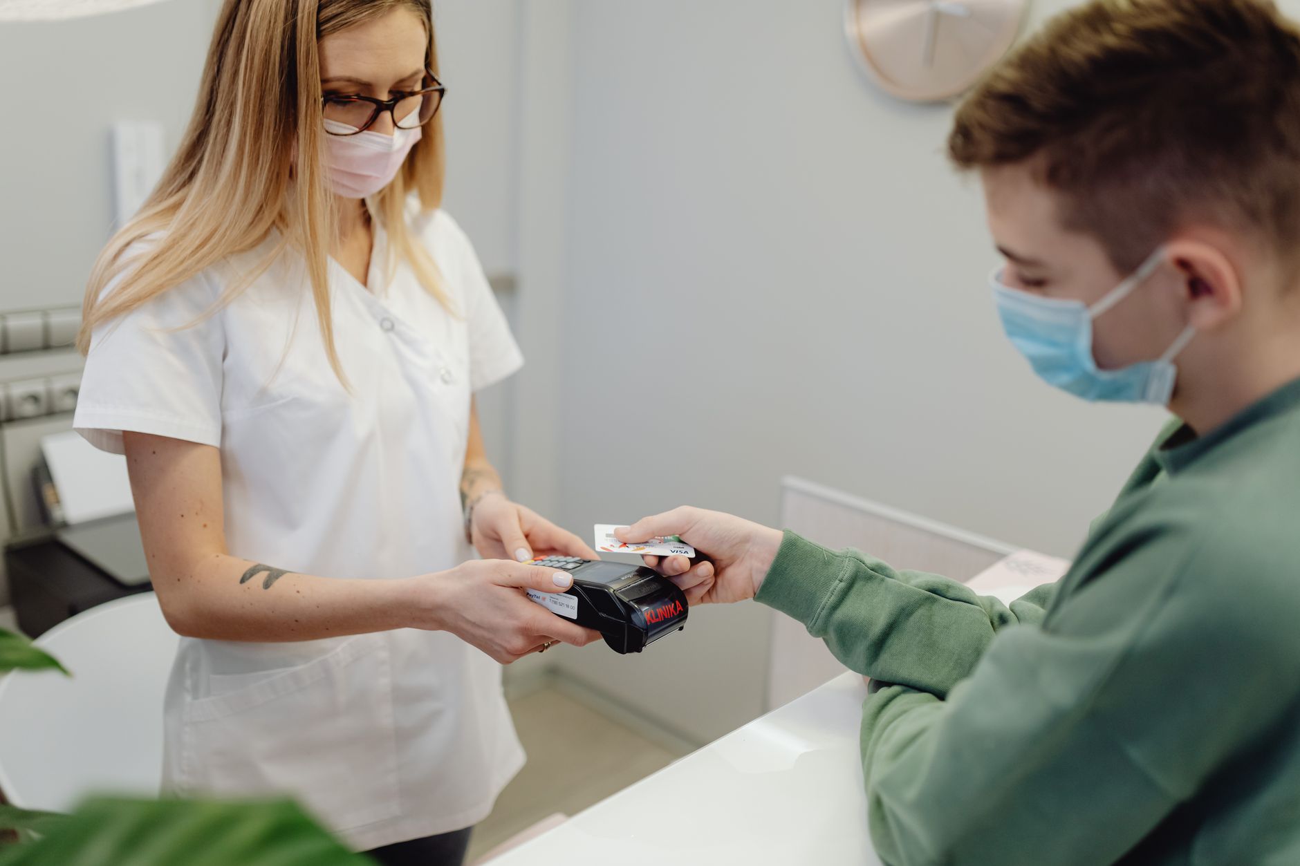 A healthcare professional processes a patient's card payment at the clinic reception.