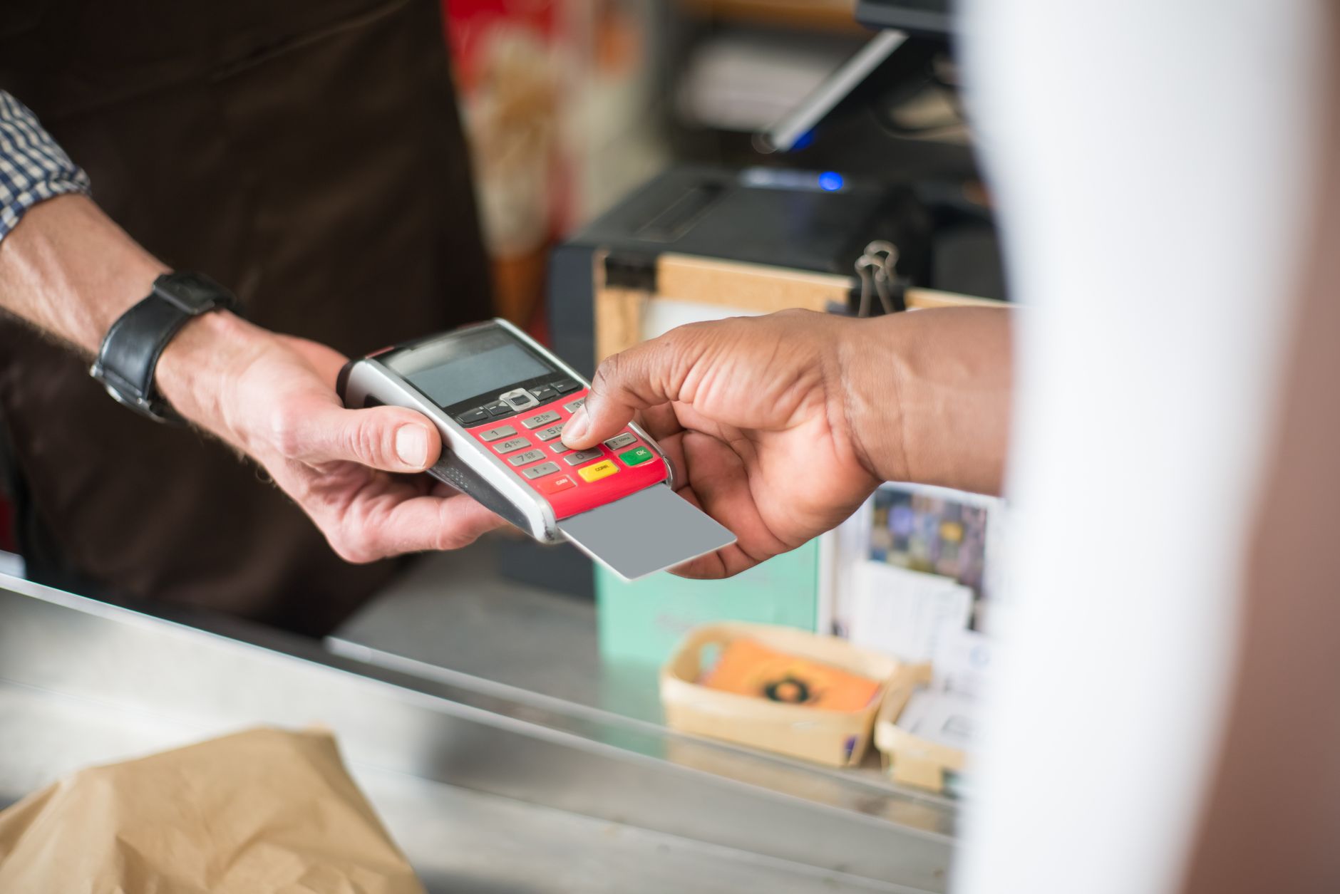 Manter saldo em euro rende? Entenda as contas com juros A customer uses a card for a contactless payment at a retail store. Business and consumerism concept.