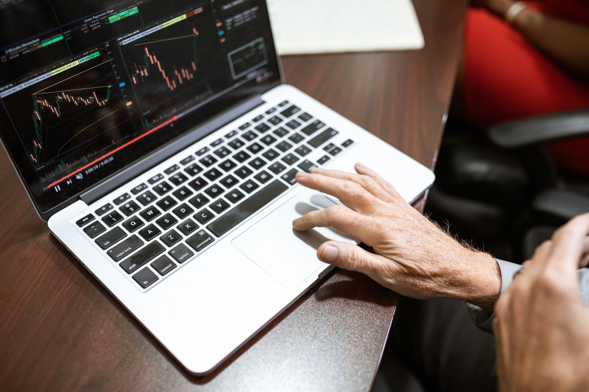 Pessoa analisando gráficos de euro e dólar em uma mesa de trabalho