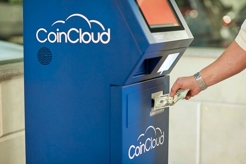 O que é DCC e por que recusar a conversão em real na Europa A person using a CoinCloud Bitcoin ATM to insert cash for cryptocurrency transactions.