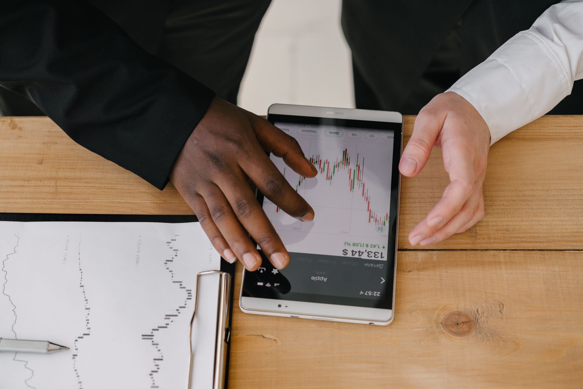 Empresário analisando gráficos de cotação de moeda estrangeira em um tablet sobre a mesa de escritório.