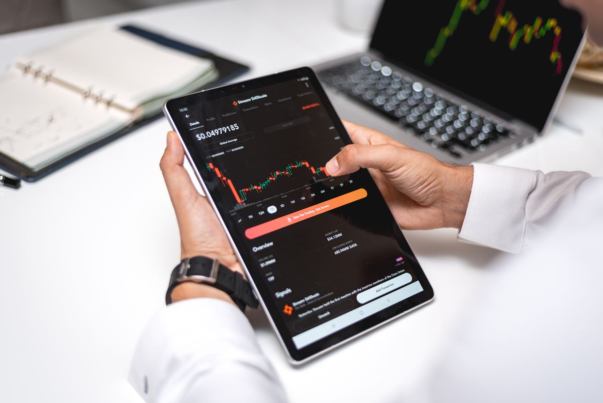 Pessoa analisando relatórios financeiros e gráficos de investimentos em um tablet.