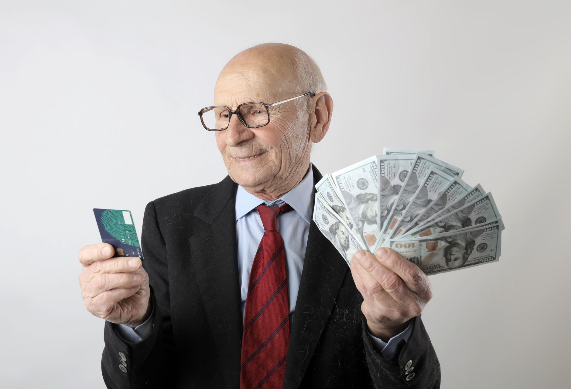 Pessoa segurando cartão de crédito e notas de euro perto de um notebook.