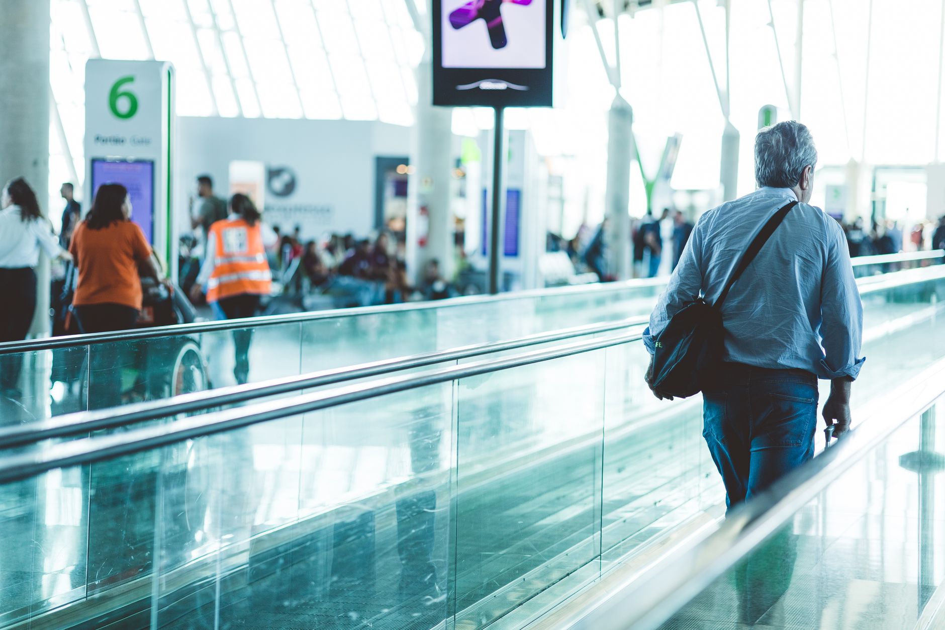 Perdeu o cartão internacional durante a viagem? Saiba agir A bustling airport scene with travelers on a moving walkway in a modern terminal.