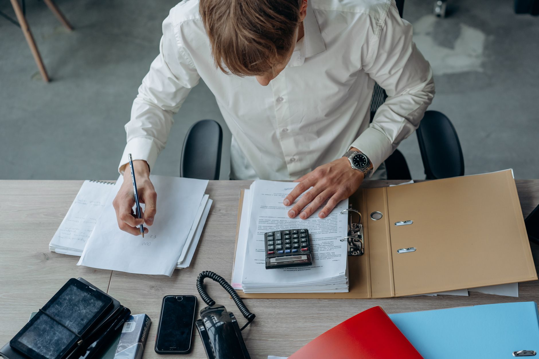 Pessoa analisando documentos financeiros e um gráfico de cotação em uma mesa de trabalho