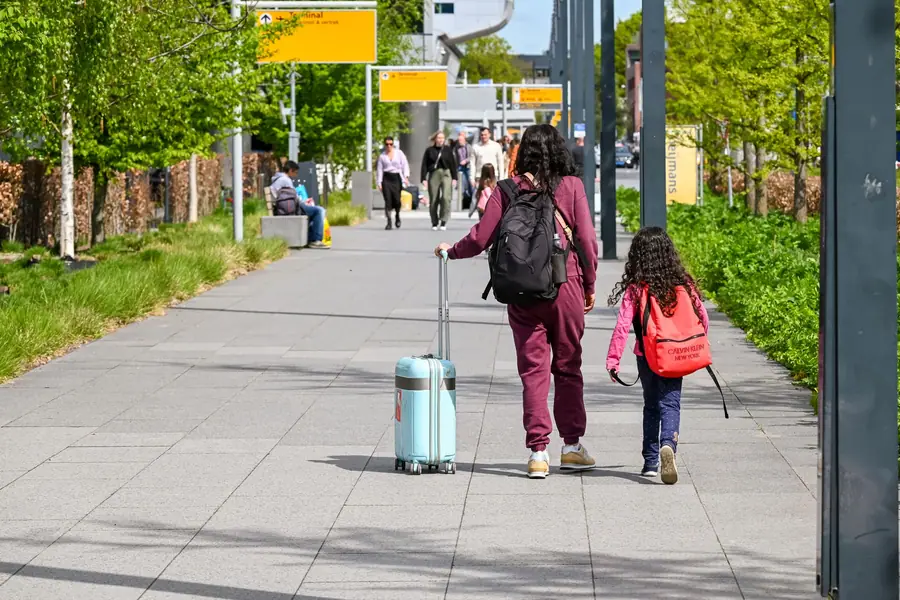 Mãe e filha caminhando com bagagem do lado de fora de um aeroporto Mãe e filha caminhando com bagagem do lado de fora de um aeroporto
