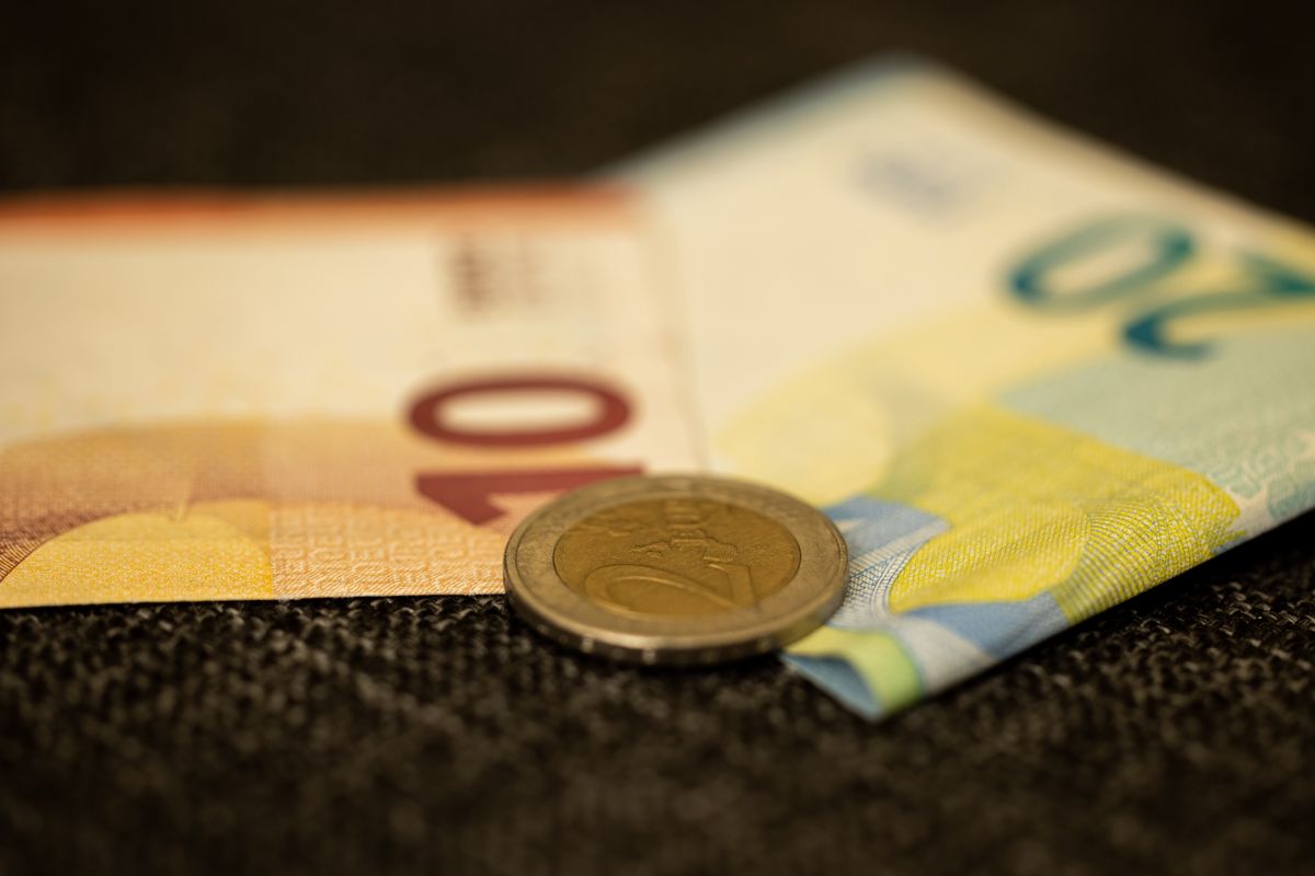 Pessoa segurando cartão de crédito internacional e notas de euro sobre mesa de café na Europa