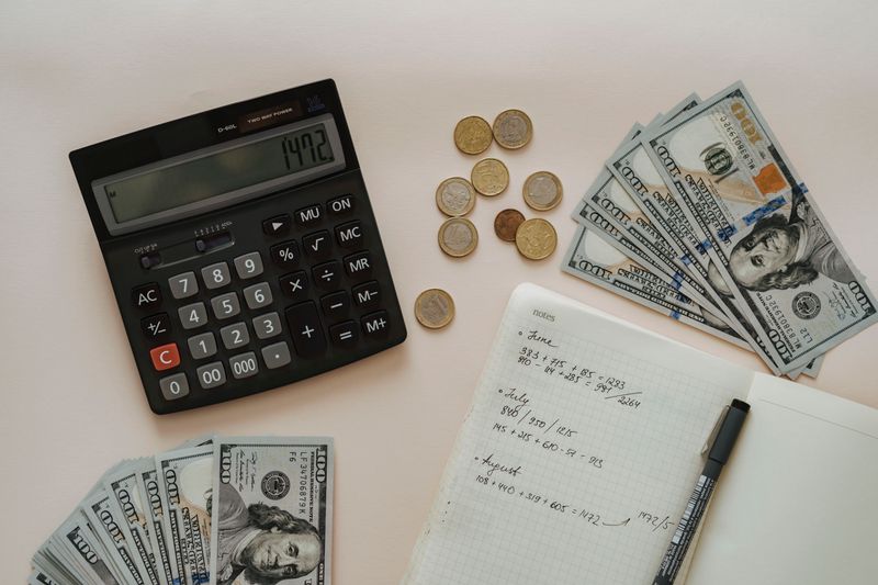 Proteção cambial para freelancer com ganho em dólar Flat lay of calculator, cash, coins, and handwritten notes for budget planning.