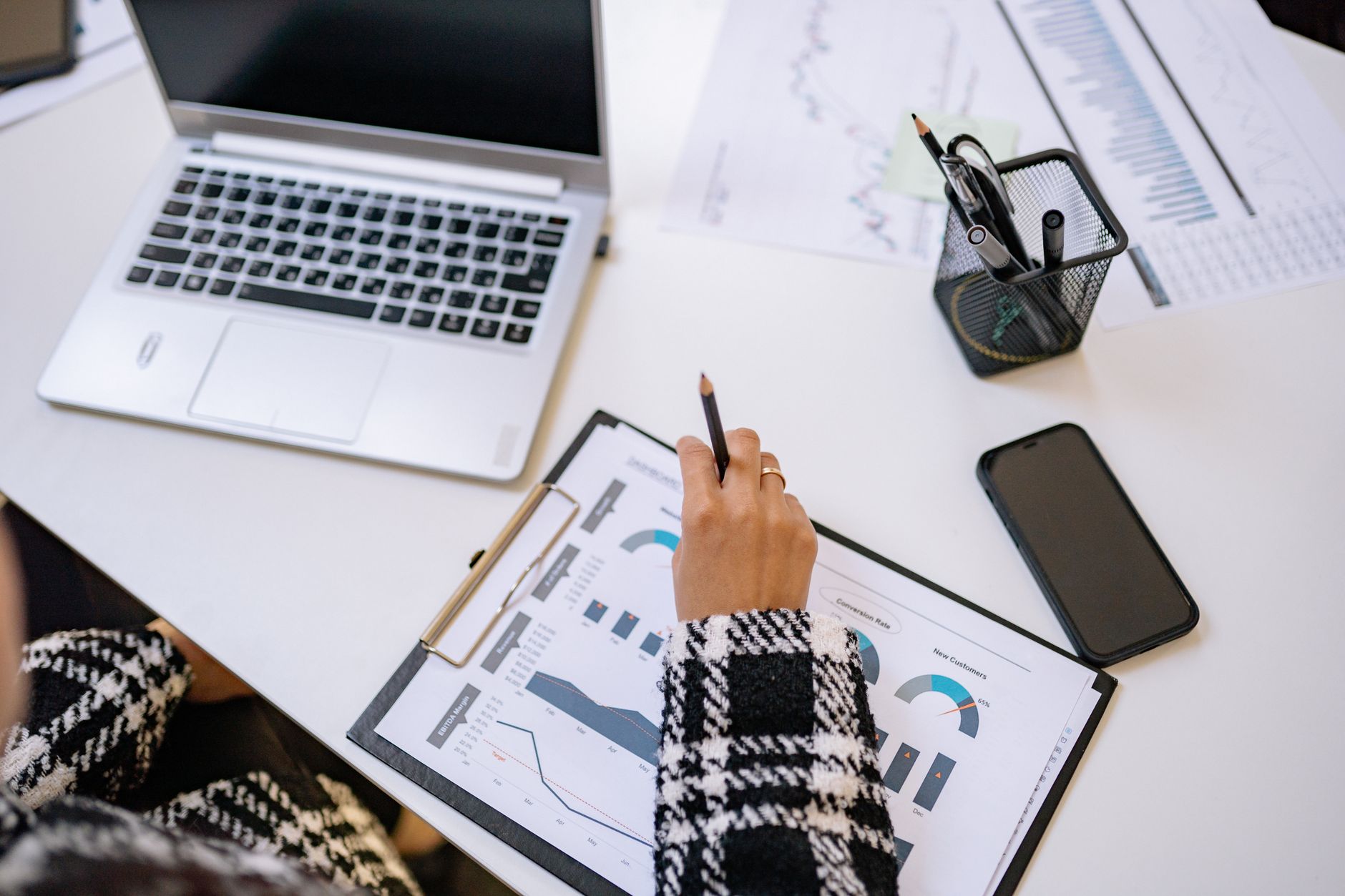 Pessoa analisando investimentos e gráficos em uma mesa de trabalho com notebook