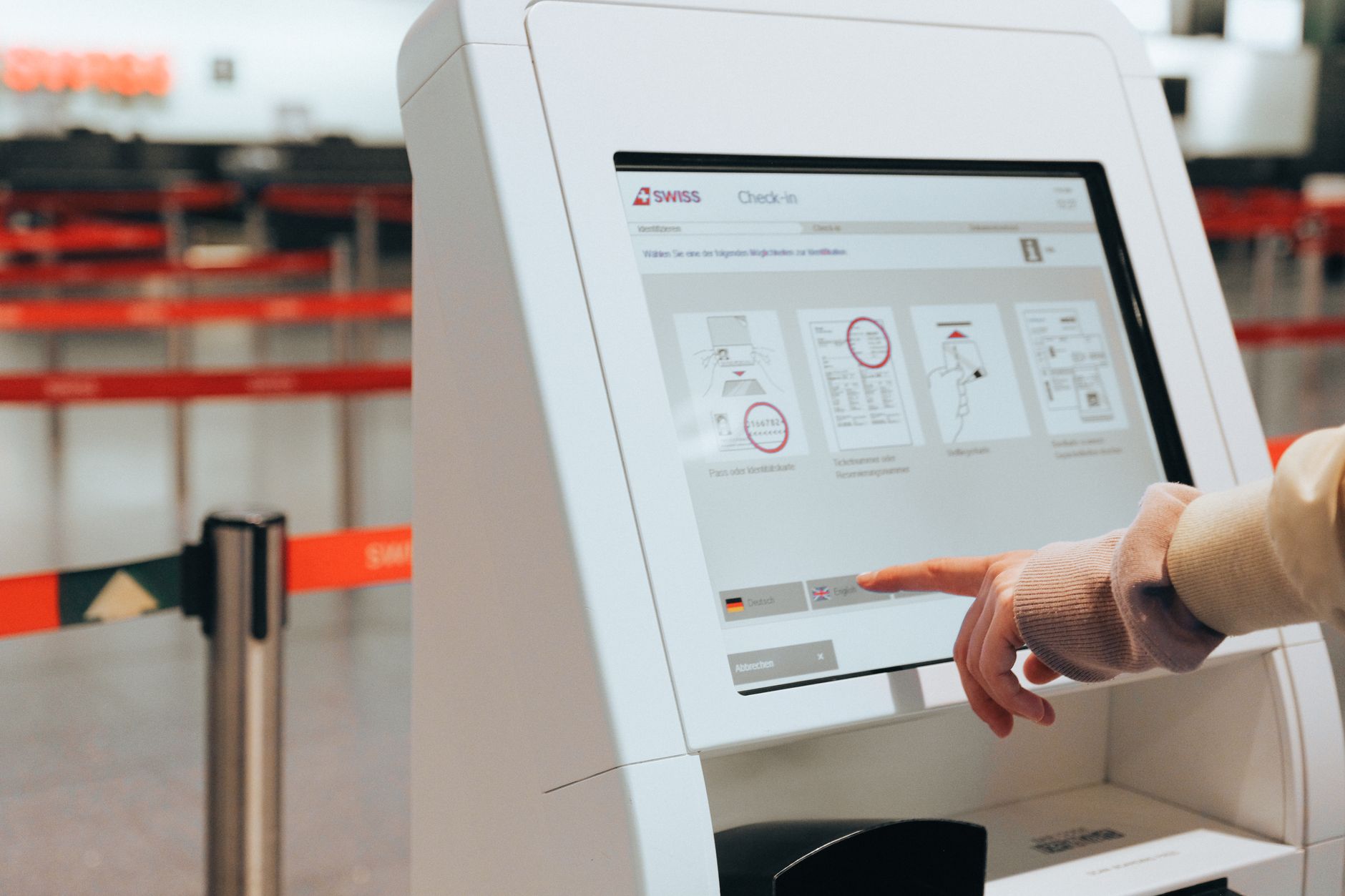 Gastos surpresa no câmbio da viagem: como se preparar Passenger using self-service check-in kiosk at airport for convenient travel experience.