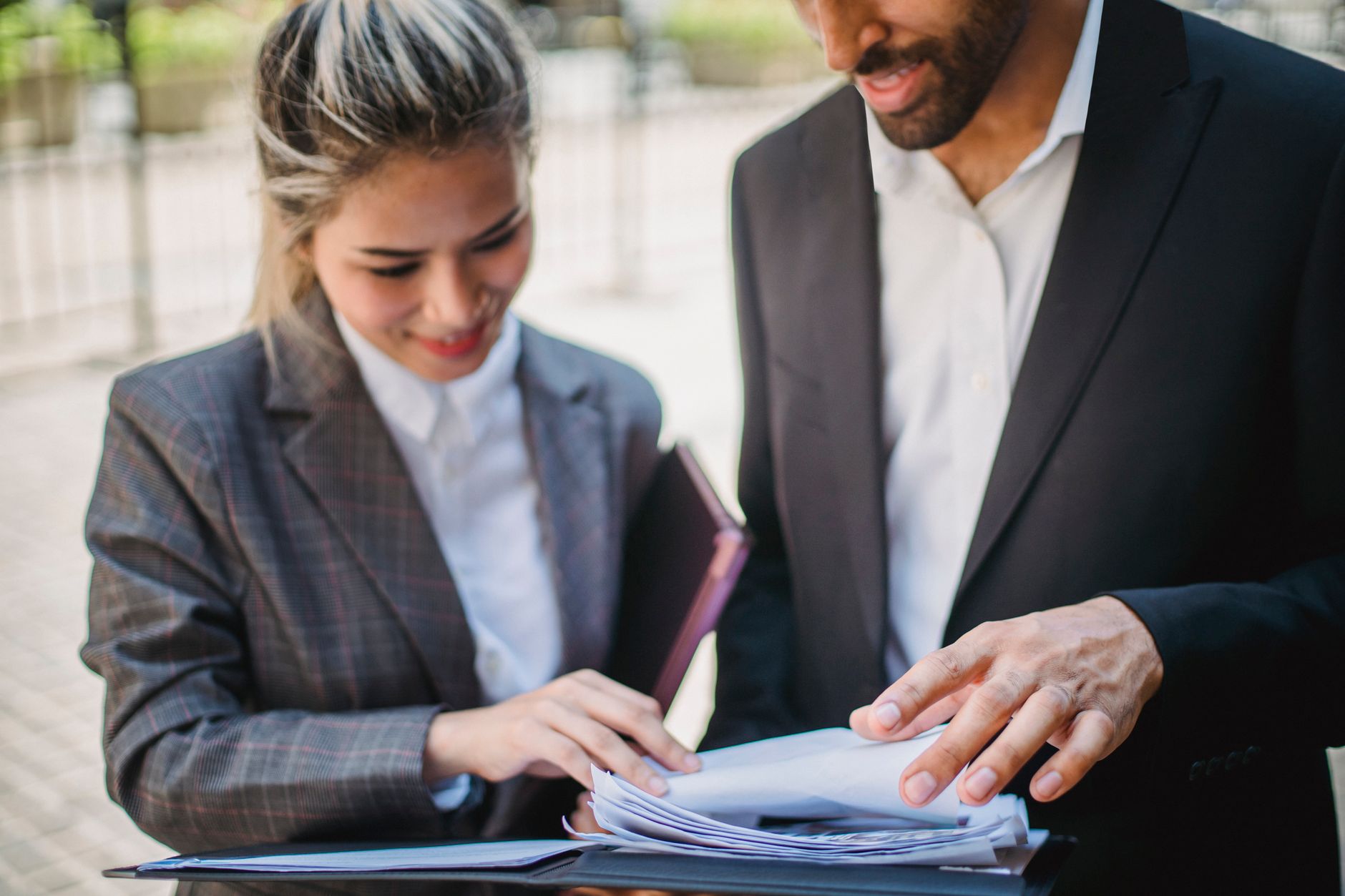 Qual o limite para levar dinheiro em espécie ao exterior Two business professionals in formal attire reviewing documents outdoors, showcasing teamwork.