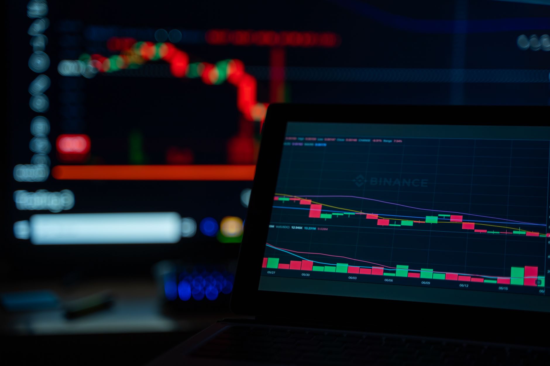 Pessoa acompanhando gráficos de cotação do dólar em um notebook e celular