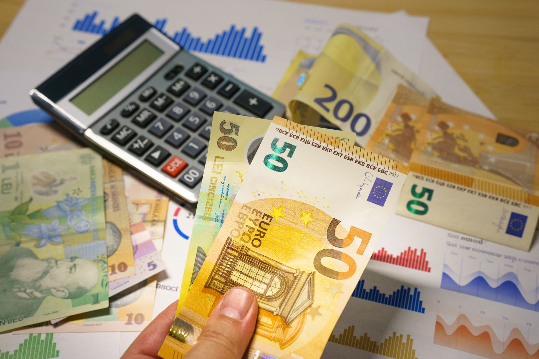 Pessoa conferindo notas de euro e reais sobre uma mesa antes de realizar uma troca de moeda.