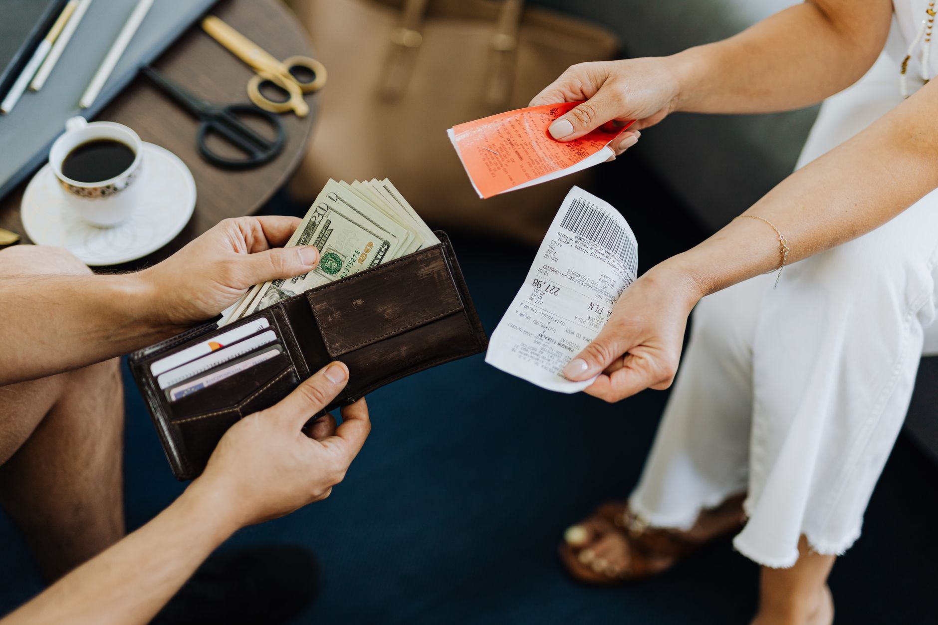 Quando o euro fica mais caro para brasileiros? Close-up of a financial transaction involving cash and receipts over a coffee table.