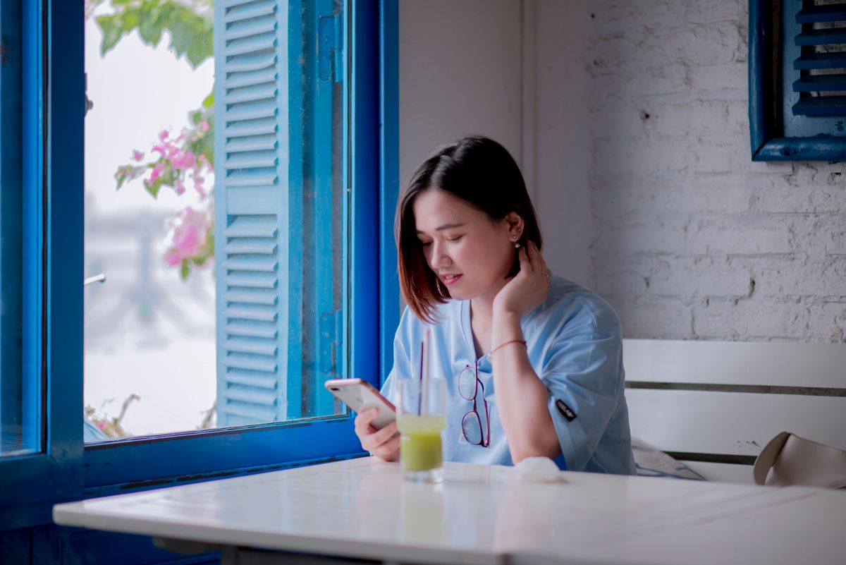 Pessoa utilizando smartphone e laptop em uma mesa de café na Europa.