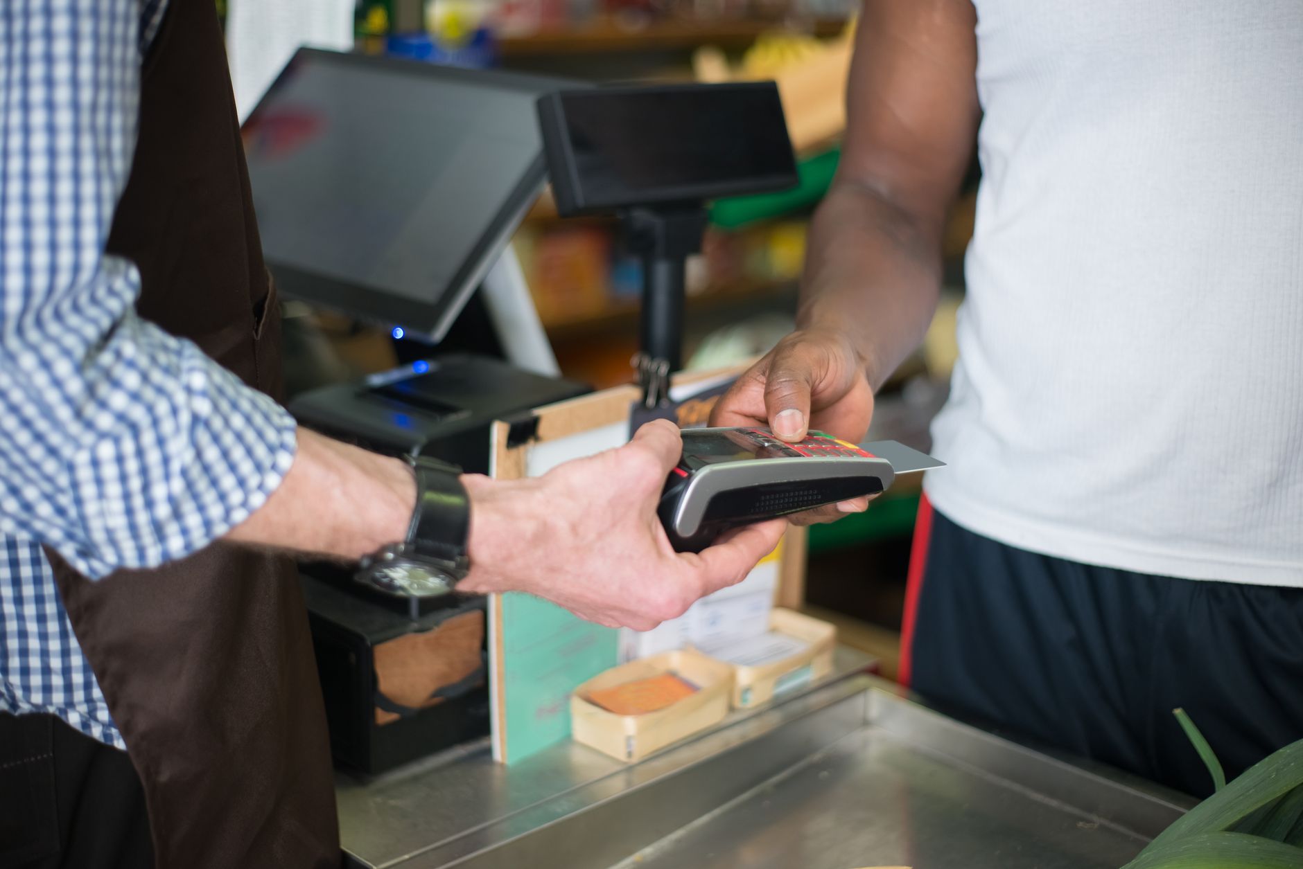 Quanto de euro levar para 10 dias na Europa? A customer making a payment with a credit card at a store checkout counter using a card reader.