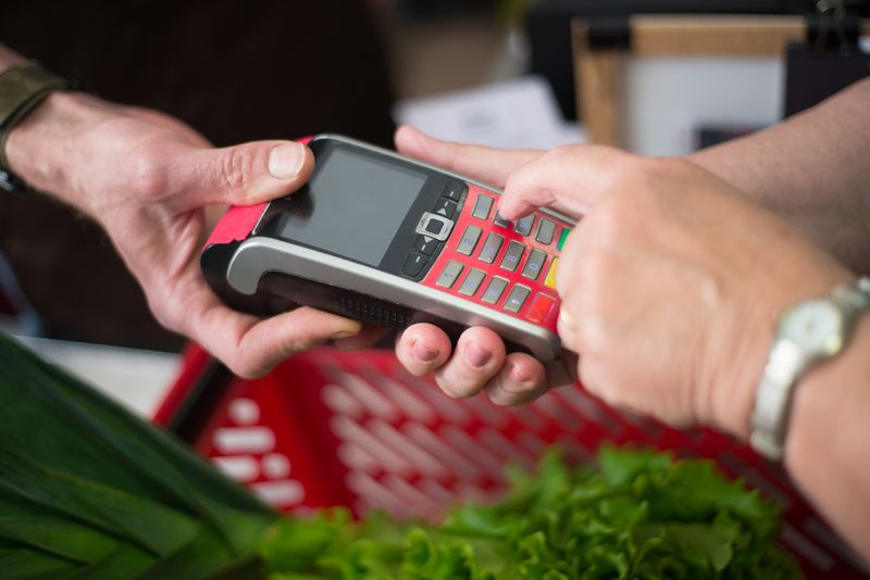 Quanto é 1 real em euro? Entenda a conversão e a cotação Two people making a cashless payment at a grocery store with a credit card terminal.