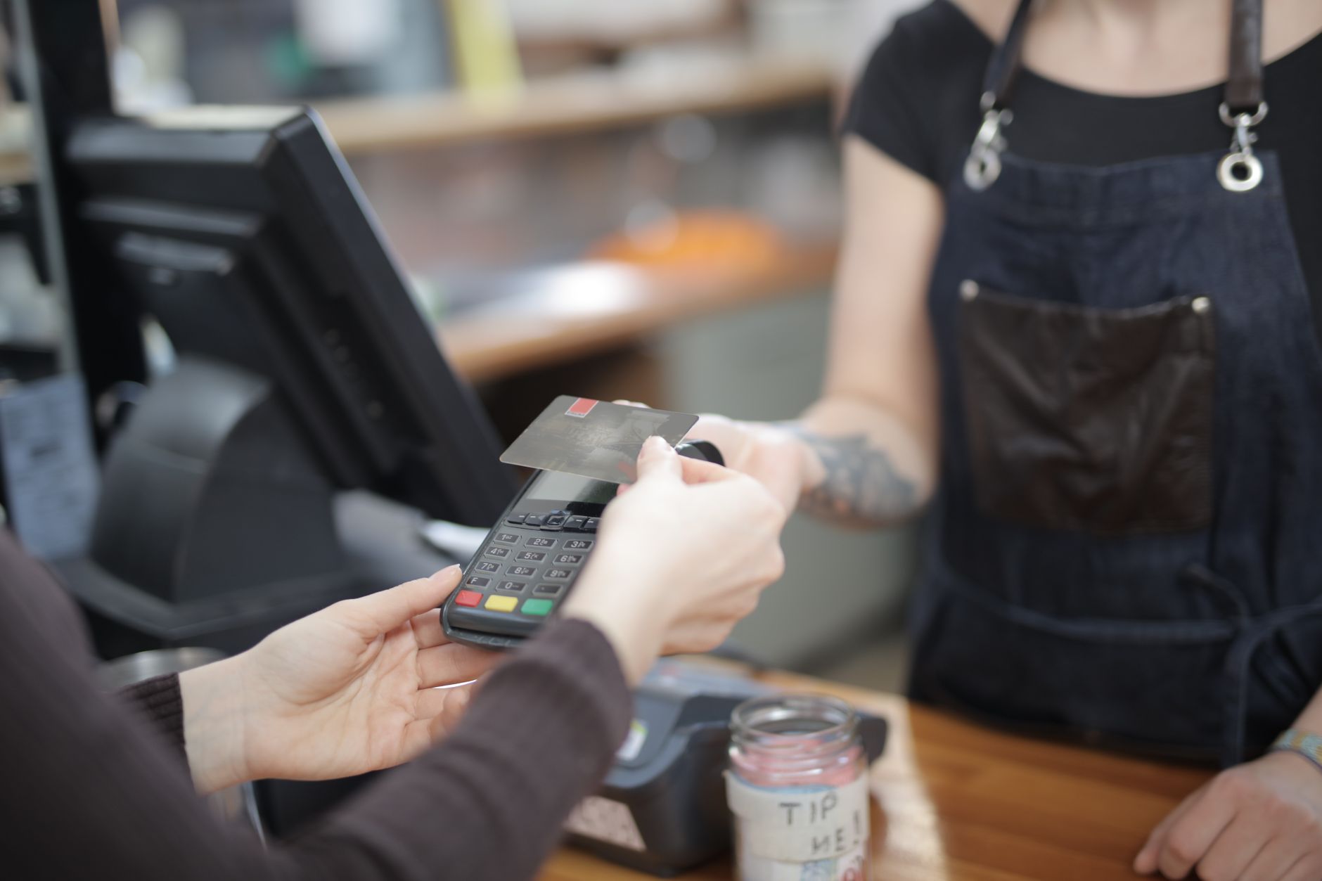 Quanto custa converter 2.000 euros em reais hoje Close-up of customer and cashier during a credit card transaction at a store counter indoors.