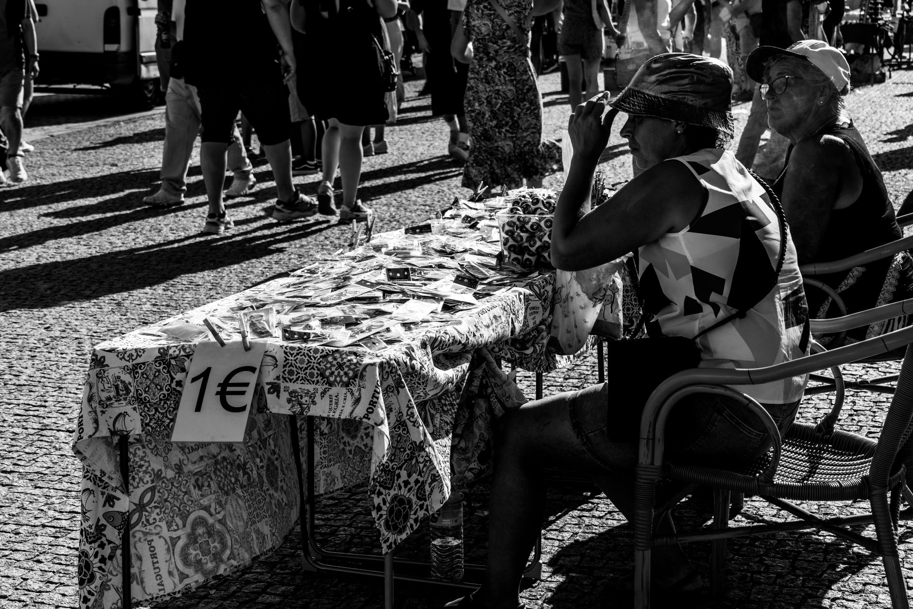 Real para euro: como calcular a conversão Black and white photo of people at a street market in Porto, Portugal, selling goods.