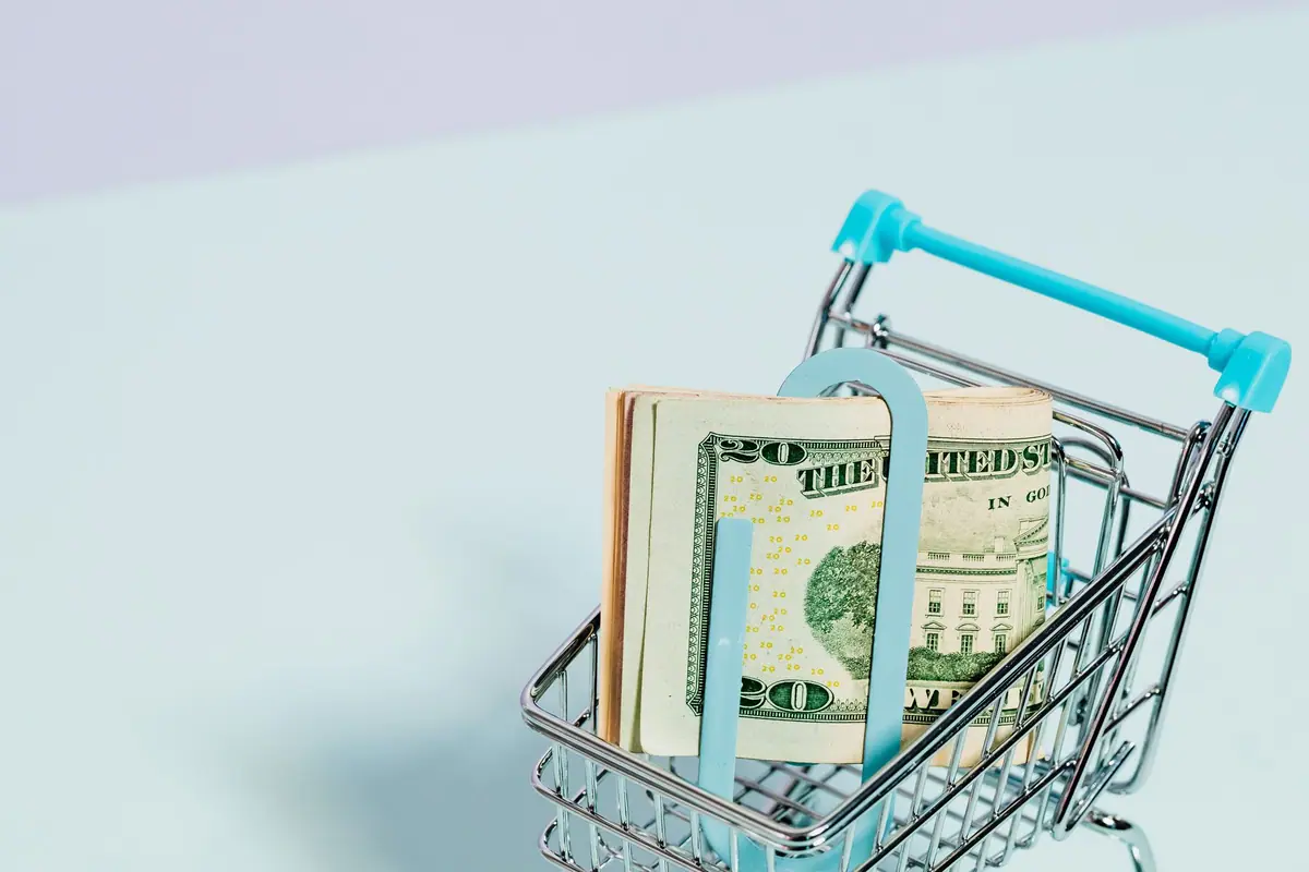 Carrinho de compras com uma pilha de notas de dólar