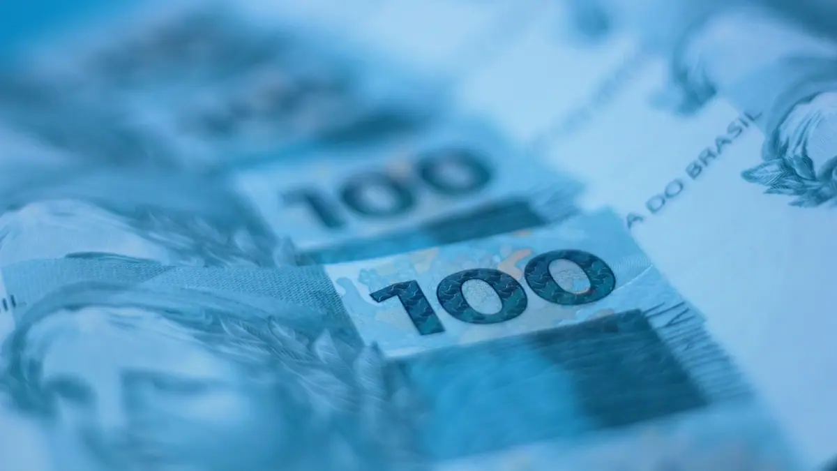 Notas de 100 reais em close sobre uma superfície escura