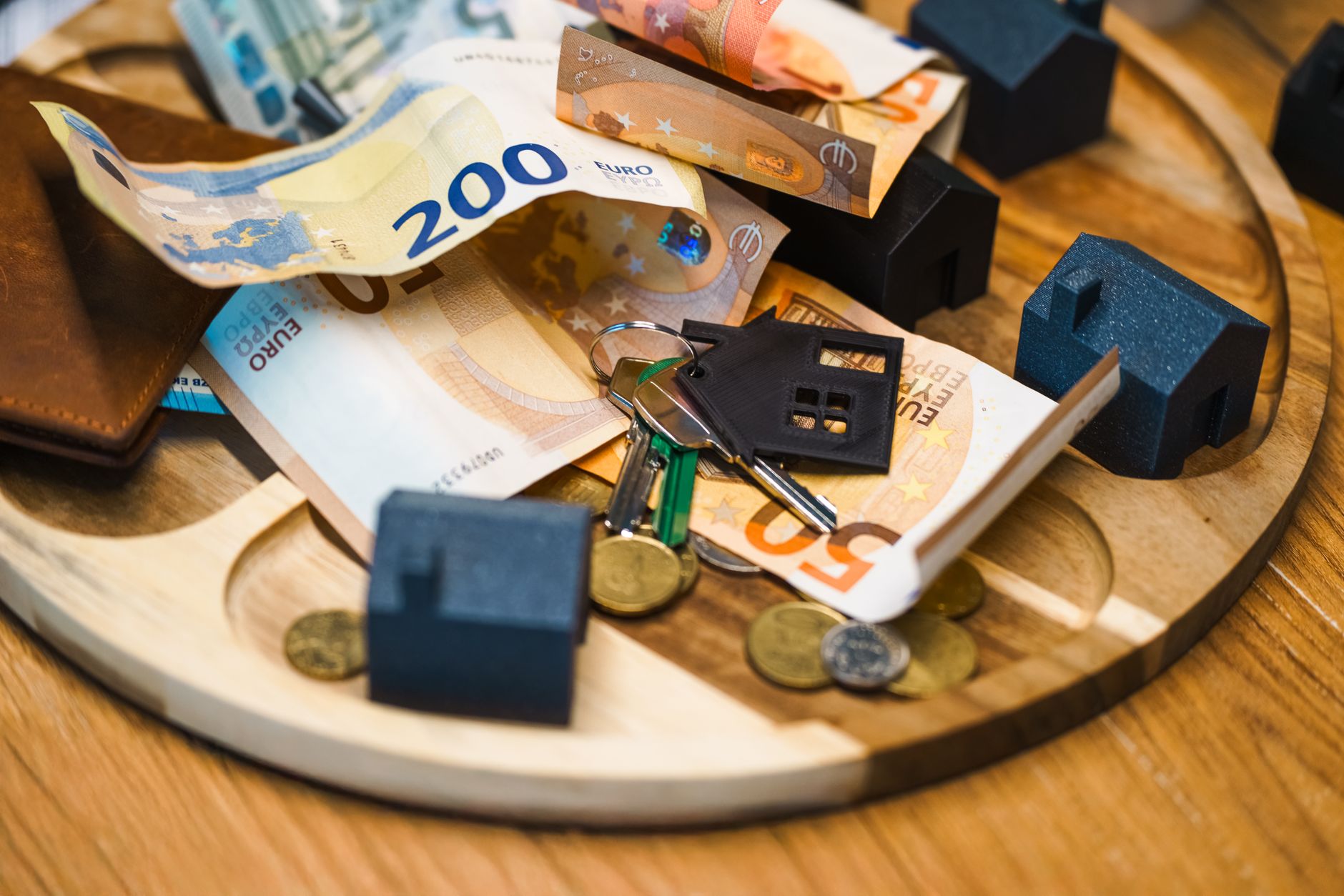 Como Funciona a Tributação de Investimentos em Euro Euro currency, keys, and miniature houses symbolize real estate and finance concepts.