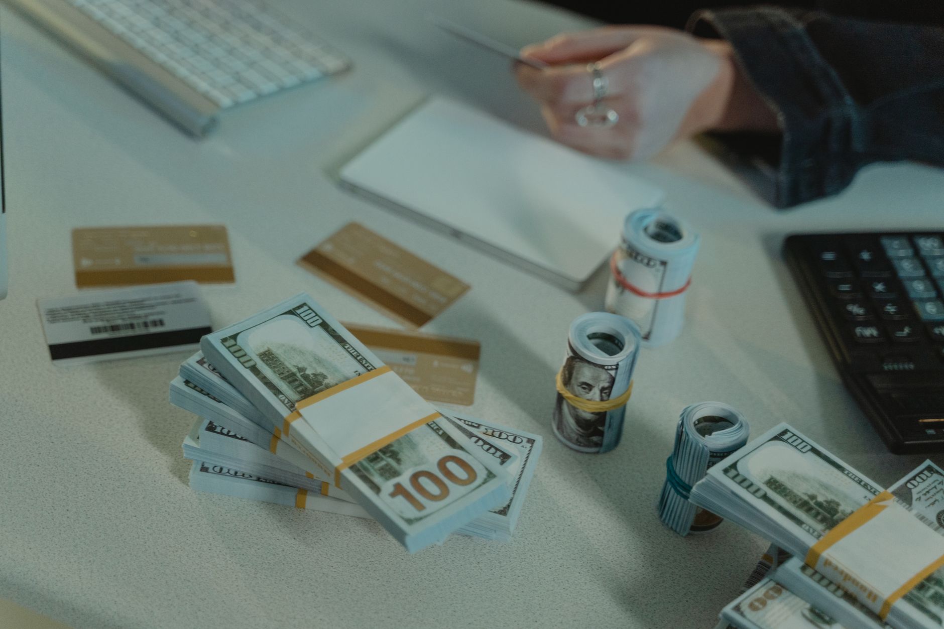 Pessoa organizando documentos, cartão e notas de dólar sobre uma mesa antes de uma viagem.