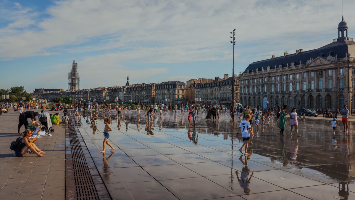 Família com crianças caminhando em uma praça europeia durante as férias.