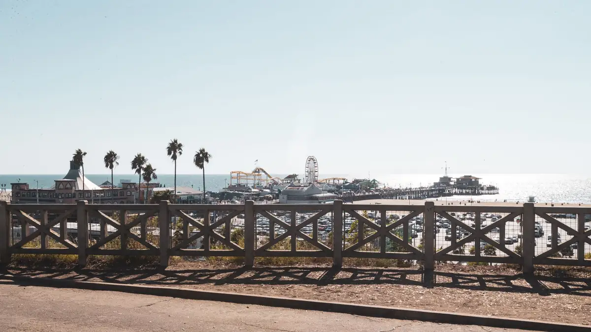 Praia de Santa Monica com palmeiras e o píer ao pôr do sol