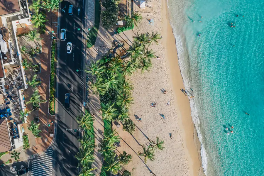 Vista aérea de uma praia tropical com estrada ao lado e águas turquesa