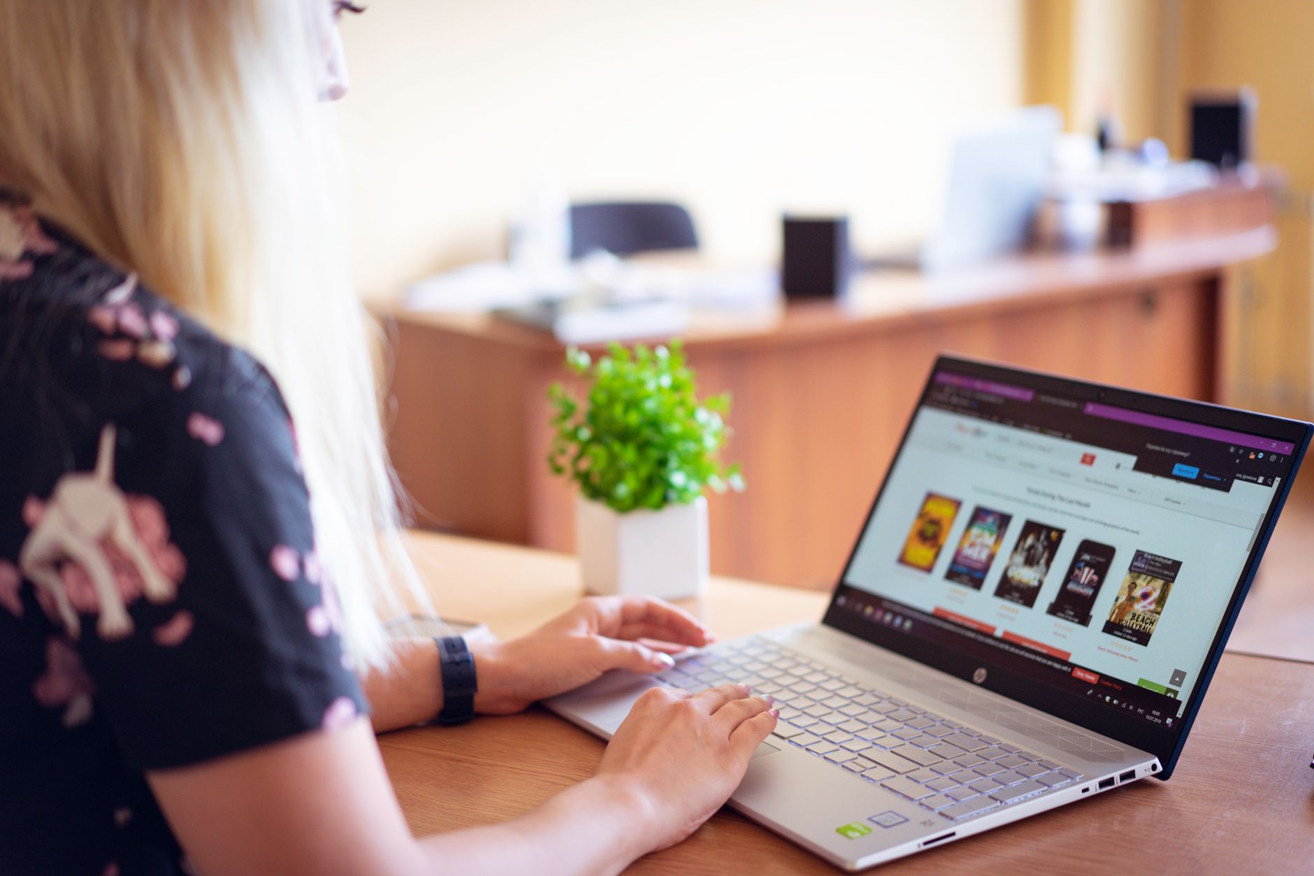 Emissor do Sebrae: para que serve e quando usar A woman browsing an online store on a laptop in a modern home office setting.