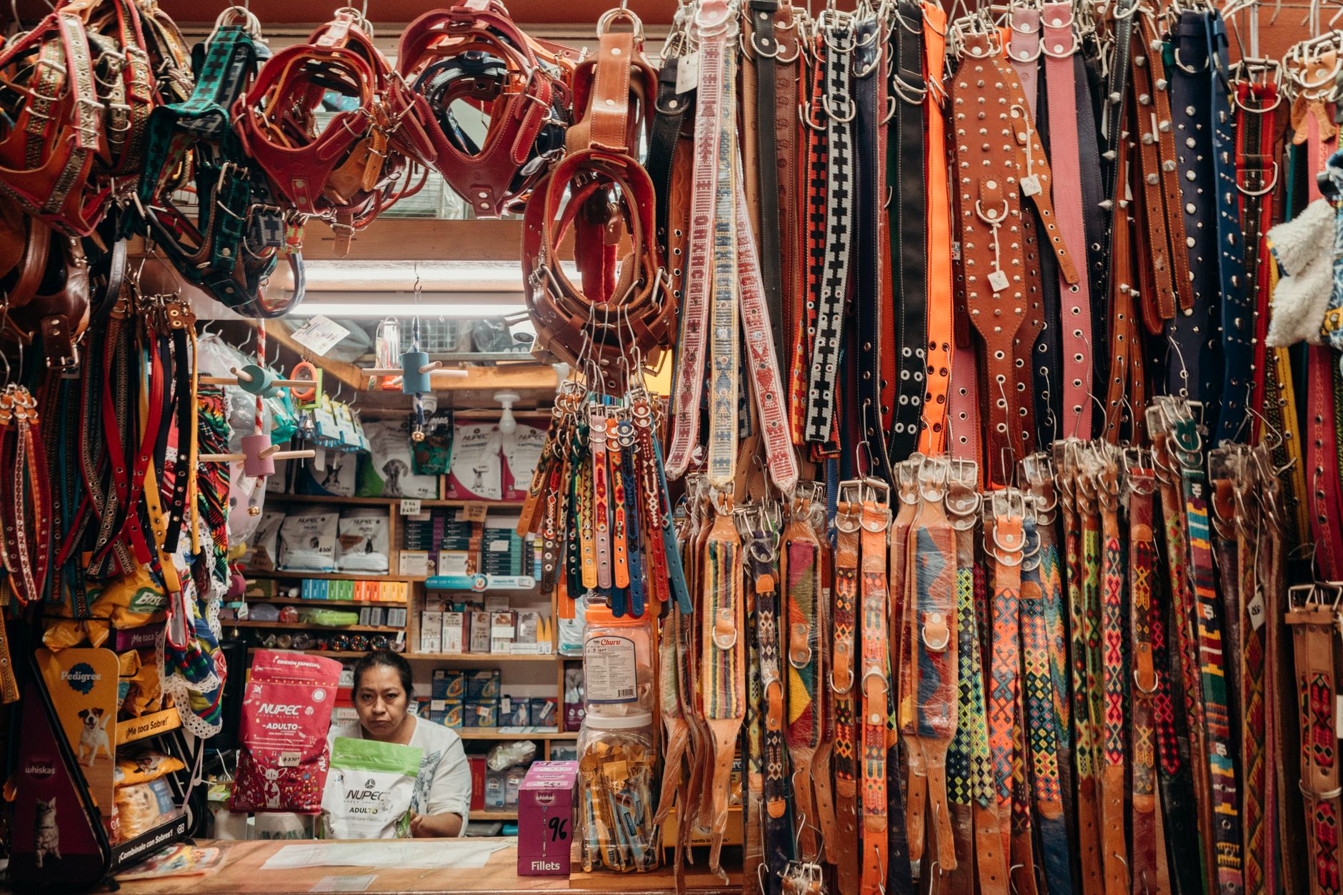 Como emitir nota fiscal: guia para começar Colorful leather pet collars at an indoor market stall with a vendor.