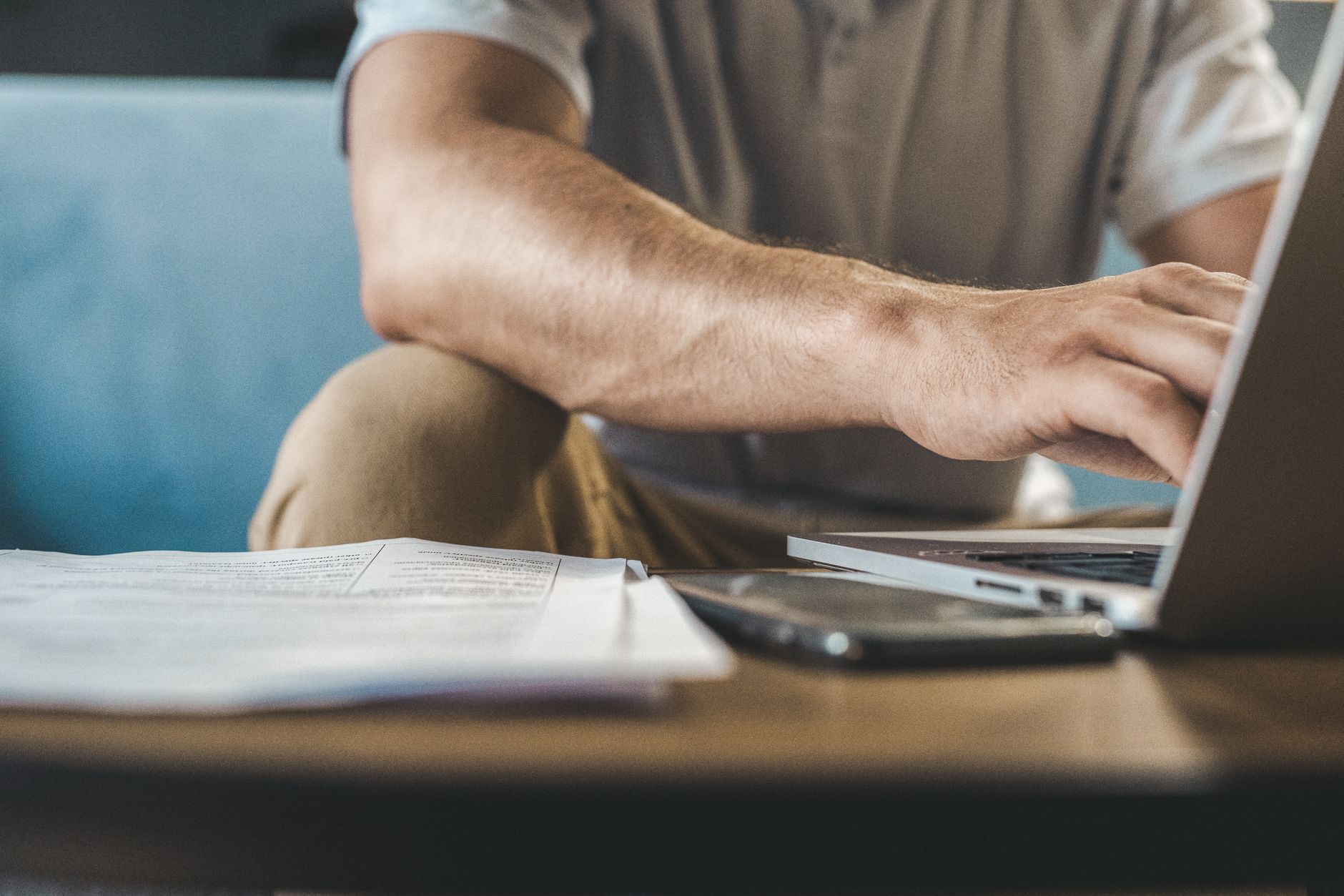 Pessoa dona de pequeno negócio confere documentos e dados em um computador antes de emitir uma nota fiscal.