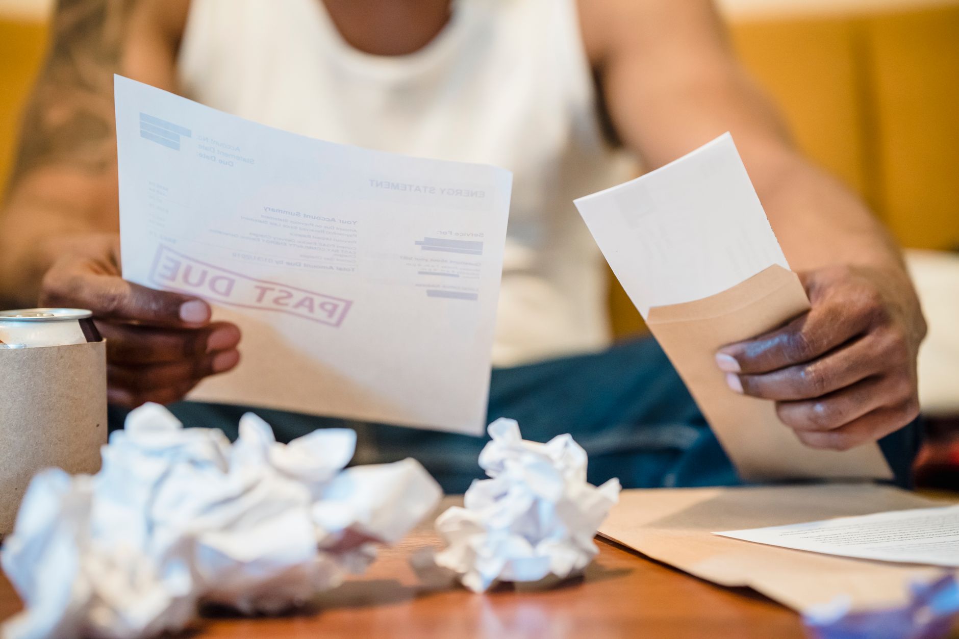 Microempreendedora conferindo um boleto e documentos financeiros em uma mesa de trabalho.