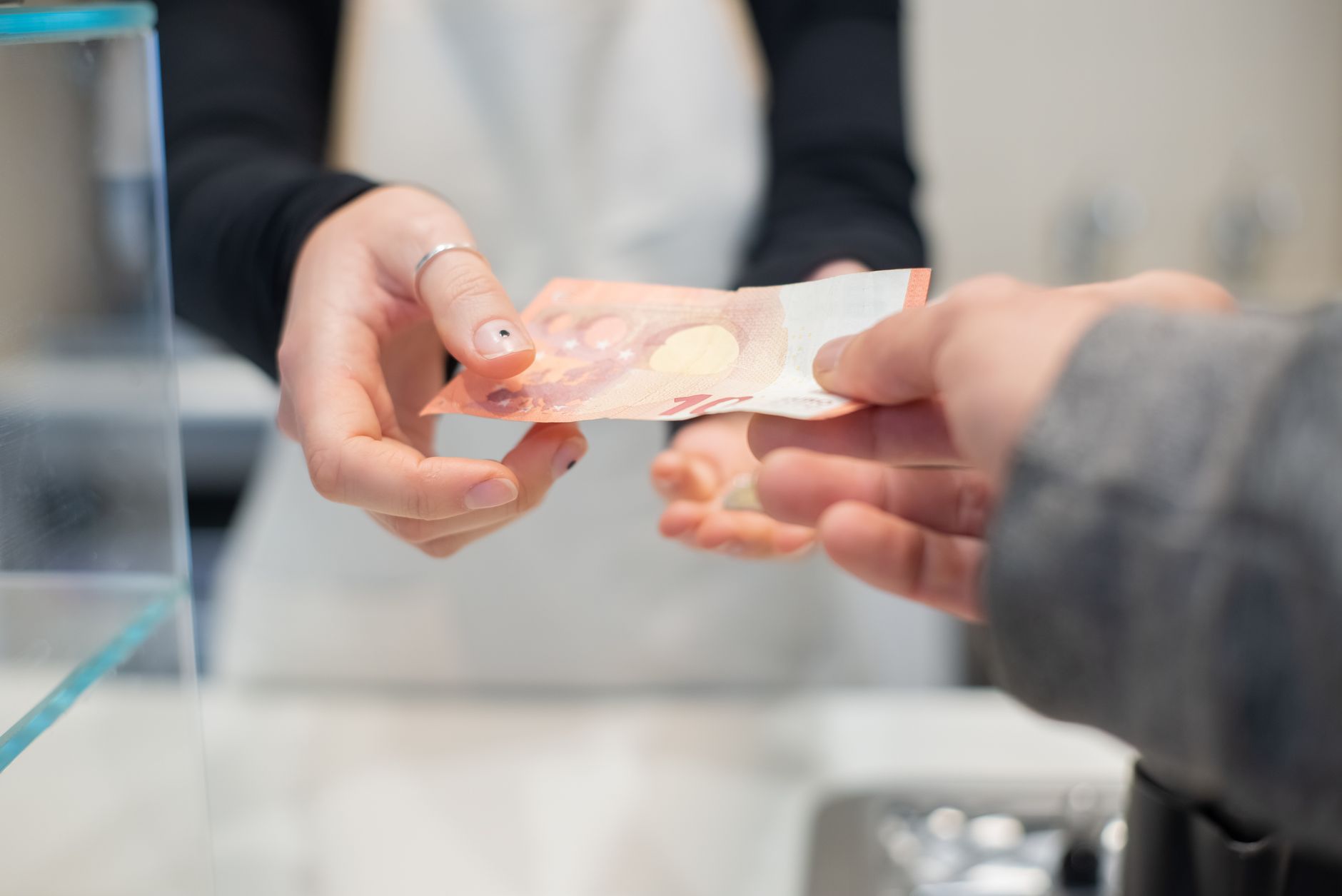 Comerciante conferindo uma venda no caixa enquanto entrega um comprovante ao cliente
