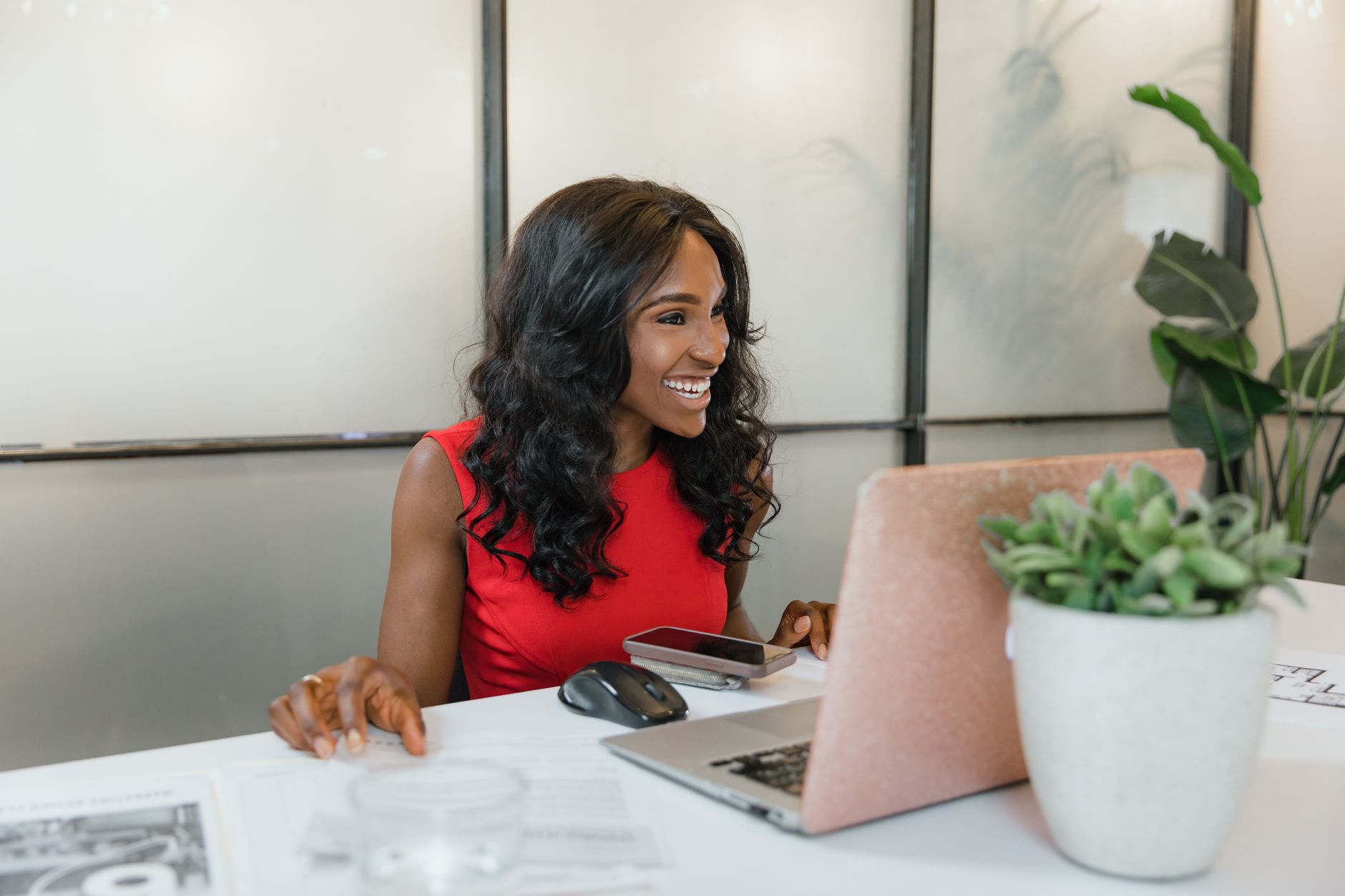 Como emitir NFS-e em São Paulo capital Professional black woman smiling at desk using laptop and smartphone in office.