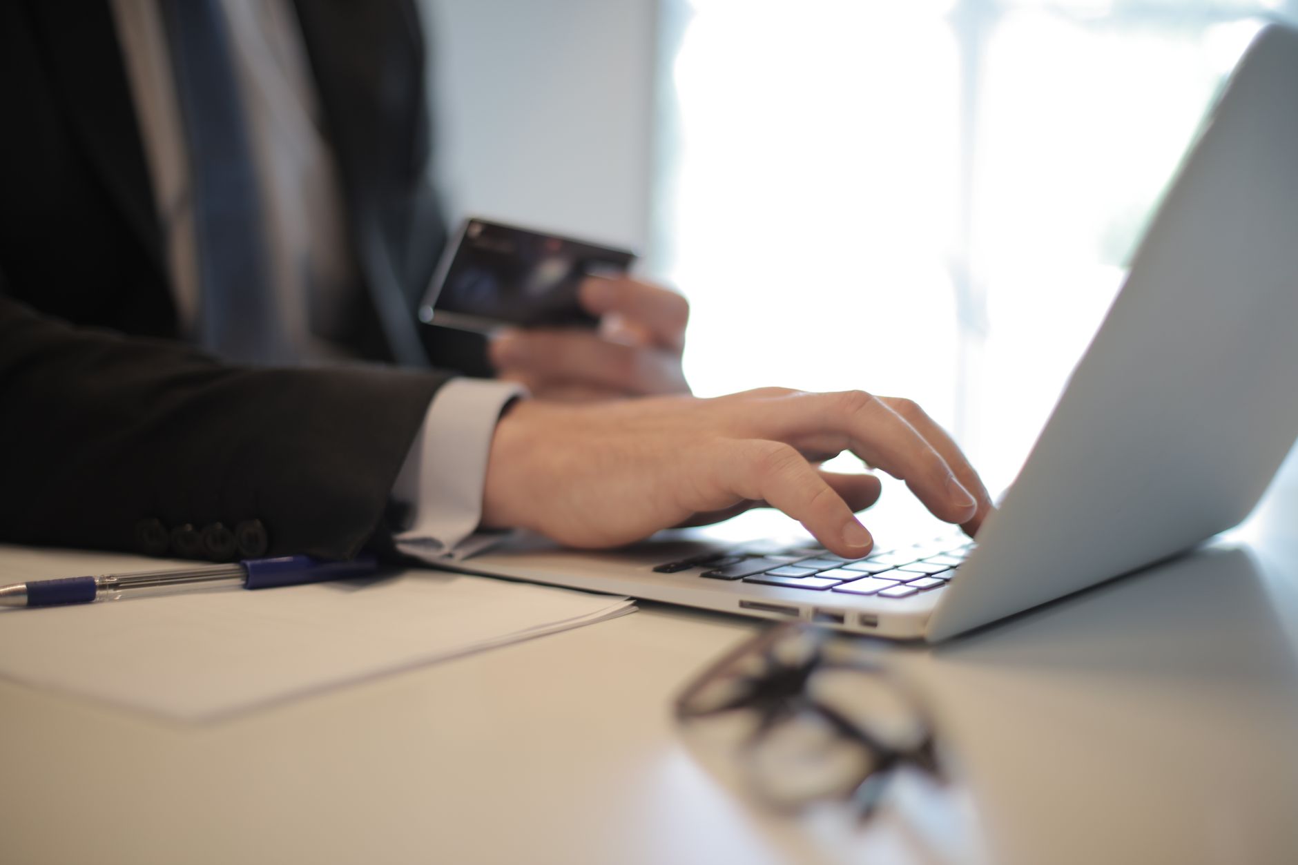 Nota fiscal avulsa na Sefaz: como emitir no seu estado Man in suit using laptop and credit card for online transaction at work.