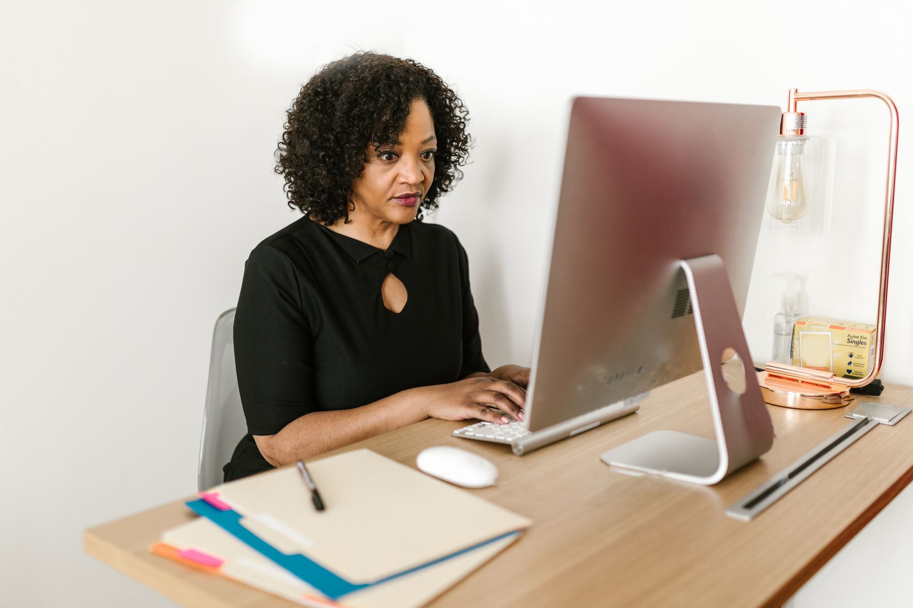 Simples Nacional e nota fiscal: como emitir e o que muda Woman in black attire working on a desktop computer in an office environment.
