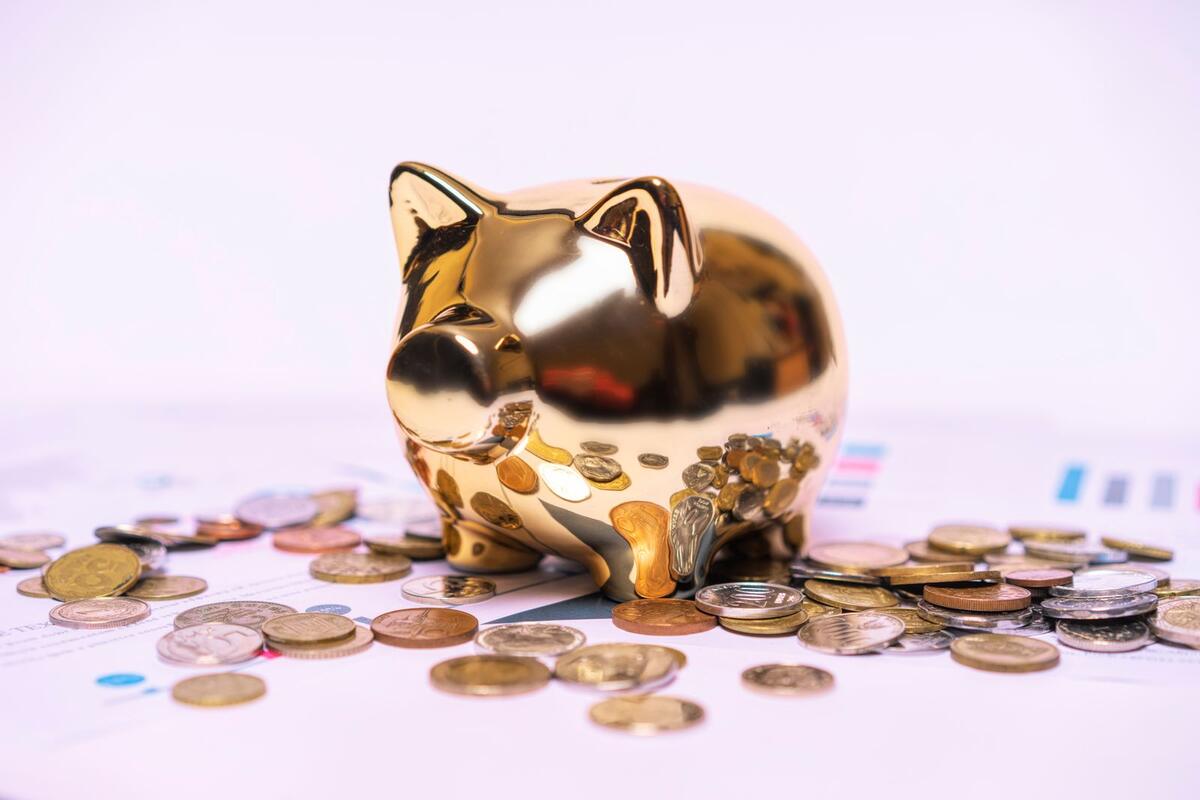 Cofrinho dourado sobre documentos financeiros com moedas