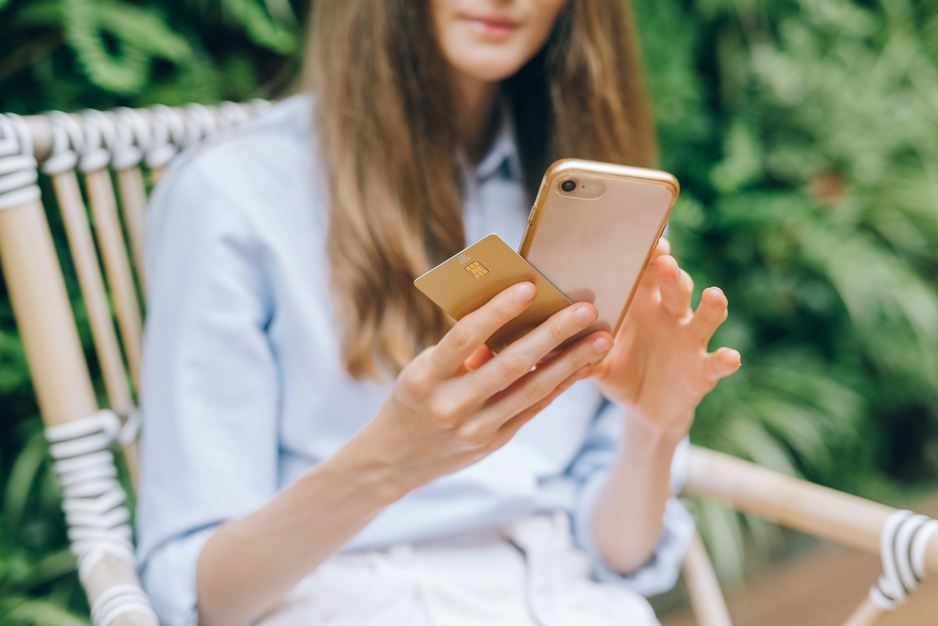 Como usar o app Serasa para consultar score e negociar dívidas A woman making an online purchase using a smartphone and credit card outdoors.