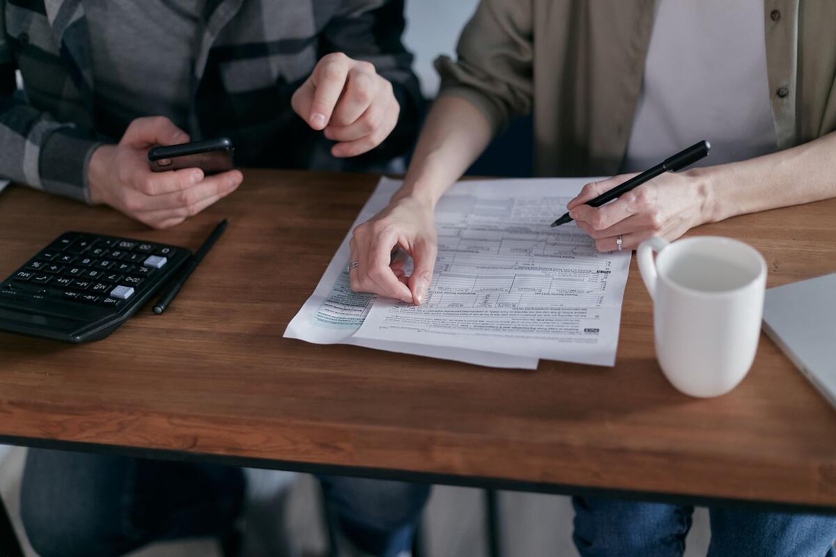 Casal organizando as finanças em casa com calculadora e documentos