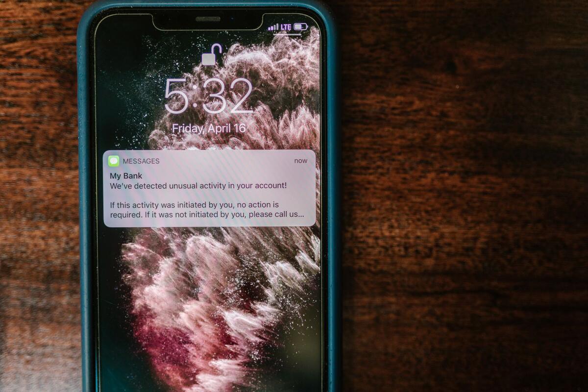 Celular sobre a mesa mostrando notificação de alerta do banco